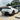 Rear three-quarter view of a white Tesla Model Y Juniper with a matte carbon fiber rear spoiler and Performance-inspired exterior styling.