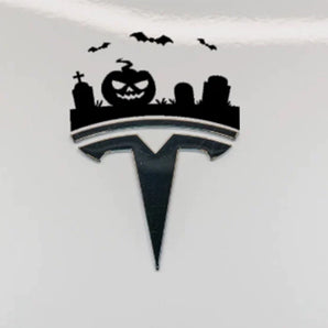 Halloween graveyard decoration sticker featuring a jack-o'-lantern, bats and tombstones above a Tesla emblem