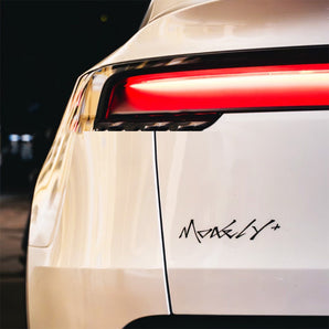Black cyber-style Model Y lettering decal on a white Tesla tailgate below the taillight