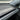 Top-angle close-up of a matte dry carbon fiber rear spoiler installed along the liftgate edge of a white Tesla Model Y Juniper.