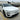 Front exterior view of a white Tesla Model Y Juniper Premium with sporty wheel covers and gloss black lower bumper trim accents.