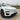 Front three-quarter view of a white Tesla Model Y Juniper Premium with gloss black Performance style fog light trim covers and sporty wheel covers.